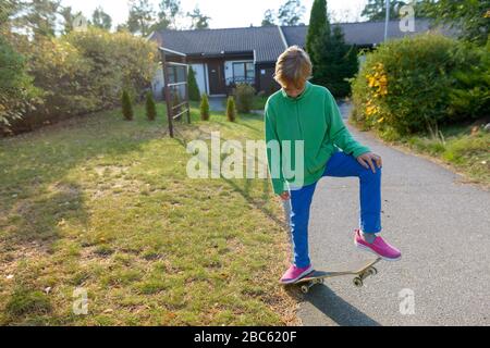 Junge hübsche junge Skateboarden im Vorgarten Stockfoto