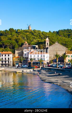 Collioure, Frankreich - 24. Februar 2020: Strandhotels in Collioure Village mit Windmühle auf Hügel, Roussillon, Vermilion-Küste, Frankreich. Es ist eine Oase der Künstler Stockfoto