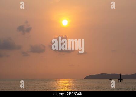 Silhouette des Fischerboots und des Leuchtturms im Meer mit Sonneneinstrahlung auf dem Meer. Stockfoto