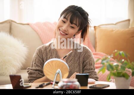 Junge chinesische Frau, die zu Hause Make-up anwendet Stockfoto