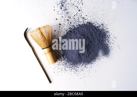 Haufen matcha-blaues Teepulver und Bambusschasen isoliert auf weißem Hintergrund, Ansicht von oben. Stockfoto