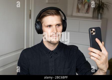 Junger Mann, der Videokonferenzanrufe über Smartphone führt. Home Office. Bleiben Sie zu Hause und arbeiten von zu Hause Konzept während Coronavirus Pandemie Stockfoto