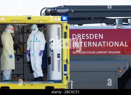 02. April 2020, Sachsen, Dresden: Medizinisches Personal steht beim Eintreffen eines Rettungsflugzeugs mit einem schwer erkrankten Covid 19-Patienten aus Frankreich in einem Krankenwagen am Internationalen Flughafen Dresden. Das Flugzeug Learjet 45 kam aus Metzger und landete am Nachmittag auf dem Flughafen Dresden. Wie das Universitätsklinikum Dresden auf Anfrage mitteilte, werden am Abend zwei weitere französische Patienten erwartet. Das Fachkrankenhaus Coswig, das Krankenhaus Dresden-Friedrichstadt und das örtliche Universitätsklinikum würden jeweils einen der Patienten versorgen. Über ihre Identität wurde nichts enthüllt. Sachsen hatte bereits a Stockfoto