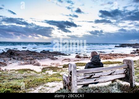 Südafrika, Cape St Francis, Sun Going Down, über den Indischen Ozean und die Wellen schlagen auf den Rocks, während sie dort sitzen. Stockfoto