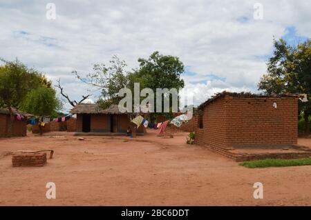 Afrikanische Häuser mit farbenfroher Kleidung zum Trocknen auf der Straße in Lolongwe, Malawi - einem der ärmsten Länder der Welt. Stockfoto