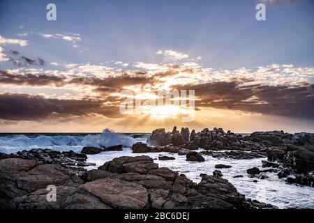 Südafrika, Cape St Francis, Sun Going Down, über den Indischen Ozean und die Wellen schlagen auf den Rocks. Stockfoto