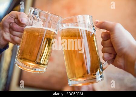 Nahaufnahme von zwei Männern, die mit Bier toasten Stockfoto