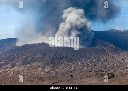 Ein erhöhter Blick auf den Berg Bromo (ausbrechend) und das Meer des Sandes, Bromo Tengger Semeru Nationalpark, Java, Indonesien. Stockfoto