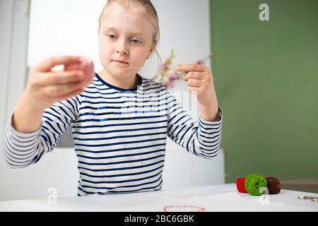 Hübsches Mädchen, das Hausarbeit während der Quarantäne verführt, Stickereien mit farbigen Fäden 1 Stockfoto