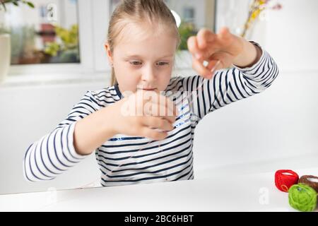 Hübsches Mädchen, das Hausarbeit während der Quarantäne verführt, Stickereien mit farbigen Fäden 2 Stockfoto