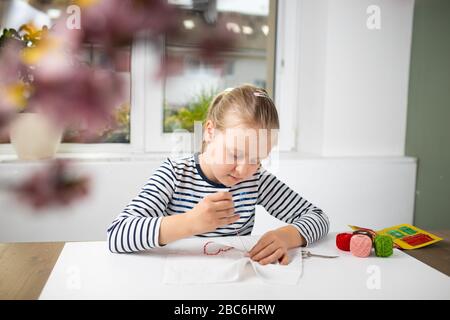 Hübsches Mädchen, das während der Quarantäne Hausarbeit vernahm, Stickereien mit farbigen Fäden 4 Stockfoto