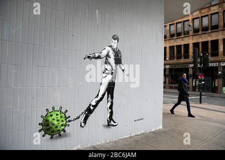 Eine Person geht an einem Kunststück des Künstlers vorbei, das als Rebel Bear bekannt ist, nachdem es an einer Wand in der Bath Street in Glasgow auftauchte. Die neue Ergänzung zu Glasgows Straßenkunst erfasst die globale Coronavirus Krise. Das Stück zeigt einen Mann, der eine Kette mit einem daran befestigten Keim zieht, während Großbritannien sich in einem Lockdown fortsetzt, um die Ausbreitung des Coronavirus einzudämmen. Stockfoto
