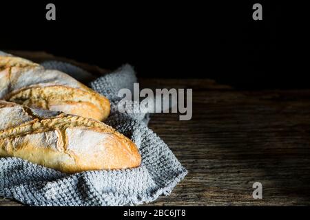 Zwei Brotsorten im Landhausstil auf einer antiken Holztafel mit schwarzem Hintergrund und Platz für das Kopieren Stockfoto