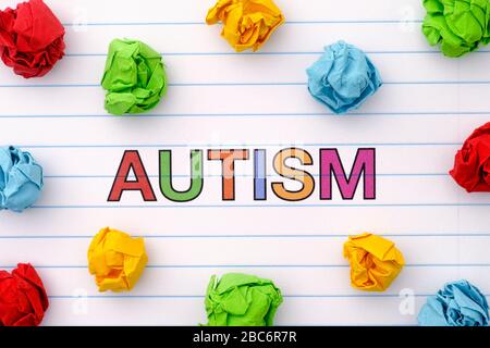 Autismus. Autismus-Spektrum-Störung. Autismus-Wort auf Notizbuchblatt mit bunten zerknautelten Papierkugeln um sie herum. Nahaufnahme. Stockfoto