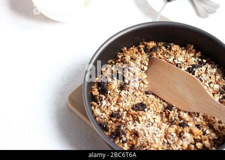Frisch zubereitete Granola in einer Pfanne. Getreide mit Nüssen und Rosinen. Getreideessen. Stockfoto