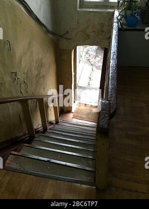 Altes Haus. Durchgang in einem verlassenen Korridor. Treppe hinunter zur Straße. Gerissene Wände. Keine Leute gehen aus Stockfoto
