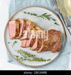 Keto-Ketogen-Diät Rindersteak, Striploin auf grauer Platte auf weißem Hintergrund. Paleo Essen Stockfoto