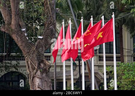 Rote kommunistische Flaggen an Masten flattern im Wind. Hanoi, Vietnam Stockfoto