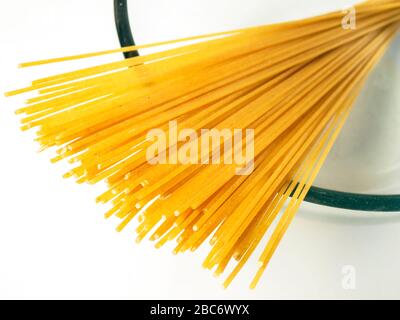 100 Gramm Vollweizenspaghetti in einer Glasschale auf einer weißen Tischdecke Stockfoto