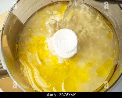 Wasser in getränkte gerollte Hafer und Rapsöl mit einer Prise Meersalz in einer Küchenmaschine geben, die für die Herstellung von alternativen Hafercreme aus Milchprodukten bereit ist Stockfoto