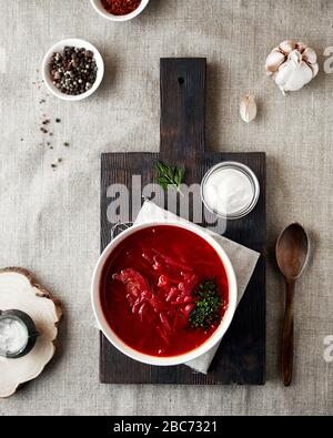 Borsch ukrainische und russische traditionelle Suppe mit Rote-Bete, Fleisch und Creme auf schwarzem Brett in der Nähe von Knoblauch, Salz und Gewürzen im Landdorfhaus Stockfoto