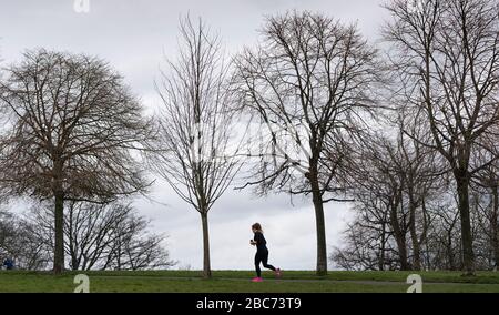 Glasgow, Schottland, Großbritannien. April 2020. Bilder von der Südseite Glasgows am Ende der zweiten Woche des Coronavirus Sperrens. Eine Frau, die allein im Queens Park läuft. Iain Masterton/Alamy Live News Stockfoto