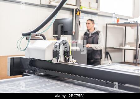 Der Techniker der Druckerei arbeitet an einer großen CNC-Computer- numerischen Steuerungs- und Schneidemaschine Stockfoto