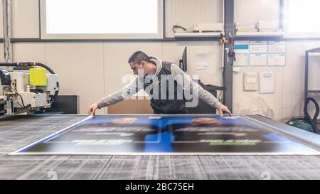 Der Techniker der Druckerei arbeitet an einer großen CNC-Computer- numerischen Steuerungs- und Schneidemaschine Stockfoto