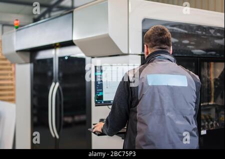 Der Druckereifachmann arbeitet an einem großen modernen 3D-Druckergerät mit Computersteuerung Stockfoto