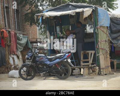 Agra, Uttar Pradesh, Indien - März 2018: Ein barber schneidet die Haare eines Kunden in einem provisorisch geöffneten Barbershop am Straßenrand in Agra. Stockfoto