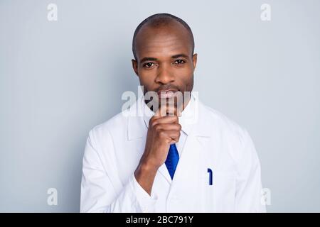 Foto des Arztes gutaussehender dunkler Hautmann freundlich lächelnd zum Patienten Virologe Haltearm am Kinn Experiment tragen weißen Labormantel blauen Krawatte isoliert Stockfoto