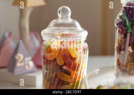 Ein altmodischer Glasbecher mit köstlichen Süßigkeiten, mit einem weiteren Mixbecher im Hintergrund und Partydekorationen Stockfoto