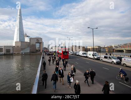 Ein erhöhter Blick auf die London Bridge und die Themse, wenn Pendler mit dem Shard in der Ferne herüber fahren. Stockfoto