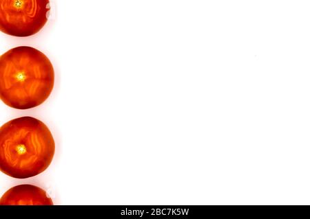 Auf dem linken Rand stehen vier Tomaten auf weißem Hintergrund Stockfoto