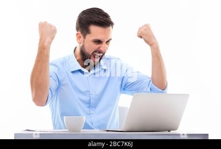 Mann vor dem Laptop mit erhobenen Armen Stockfoto