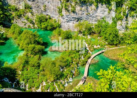 Blick hinunter auf einen Wanderweg, der an Tuffwasserfällen und türkisfarbenen Pools im Nationalpark Plitvicer Seen in Kroatien vorbeiführt. Mai 2017. Stockfoto