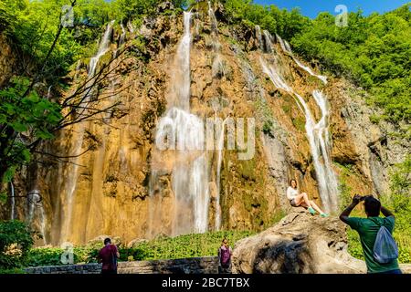 Touristen, die ein Foto vor Veliki Slap, dem größten Wasserfall im Nationalpark Plitvicer Seen, Kroatien, Europa. Mai 2017. Stockfoto