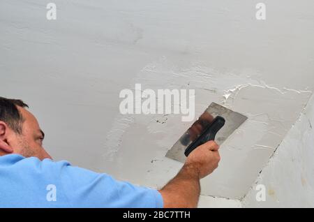 Mann glättet bei Renovierungsarbeiten eine Decke mit einem Trobel Stockfoto