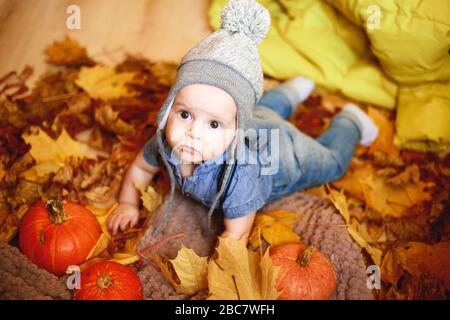 Ein kleiner Junge spielt im Herbst neben Kürbissen, Fotos in warmen Farben Stockfoto