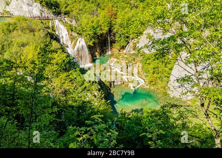 Blick über eine Reihe von Tuffstein-Wasserfällen und Pools, und ein Gehweg für Touristen, im Nationalpark Plitvicer Seen, Kroatien, Europa. Mai 2017. Stockfoto