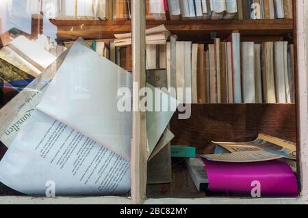 Das faszinierende helle Fenster eines gebrauchten/recycelten Buchladens. In Sicht sind mehrere Bücherregale, die die weiße Vorderkante zeigen. Die Stacheln sind es nicht Stockfoto