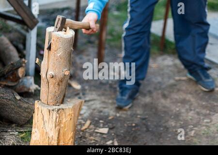 Mann hackt Holz im Hinterhof. Holzfäller schneidet Holzstämme Stockfoto