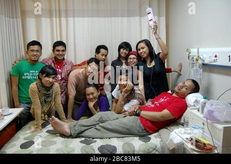 Eine Gruppe von Freunden besucht ihren Freund in einem Krankenhauszimmer. Stockfoto