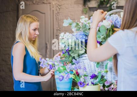 Zwei Damen Floristen machen großen Blumenkorb mit Blumen im hellen Raum Stockfoto