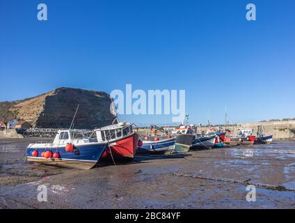 An einem sonnigen Tag mit blauen Skys gibt es im Staithes Harbour eine Reihe kleiner Boote. Stockfoto