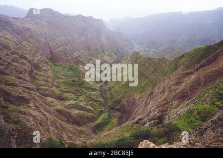 Atemberaubendes Panorama einer steilen Schlucht mit Dunstbett und üppiger grüner Vegetation im Tal des Delgadinho Bergrückens. Santo Antao, Kap Verd Stockfoto