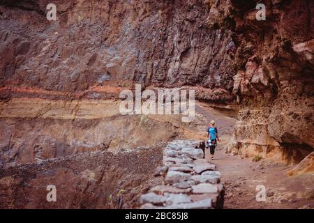 Touristenfrauen wandern weit entlang der Klippe und der felsigen gefährlichen Küste von Cruzinha nach Ponta do Sol. Riesige Bergmauern liegen auf dem Trekkkingweg. San Stockfoto