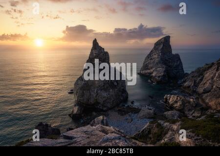 Verborgene Praia Da Ursa - Strand Ursa, Sintra, Portugal. Zwei riesige Felsen rasten abends bei goldenem Sonnenuntergang an der Atlantikküste Portugals in der Nähe von Famost Ca Stockfoto