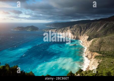 Traumhafte Atmosphäre an der malerischen zerklüfteten Küste Kefaloniens. Übergiebeltes Wetter, tiefe Wolken, stürmisches Meer und Sonnenlicht, Cephalonia, Ionische Inseln, Gr Stockfoto