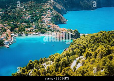 Panoramablick auf das Dorf Assos Kefalonia. Griechenland. Weiße einsame Yacht in wunderschönen türkisfarbenen Lagune Wasser von Pinien und Zypressen t umgeben Stockfoto